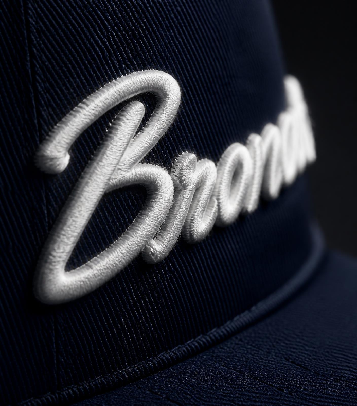 Macro detail of raised white signature embroidery on navy twill